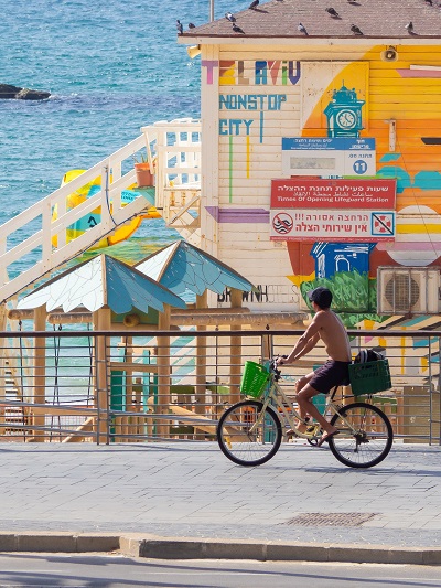 shirtless man riding bicycle colorful houses mural tel aviv israel